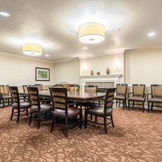 A well-lit conference room with a large table and multiple chairs arranged around it.