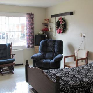 A cozy bedroom with a bed, armchairs, and decorative elements.
