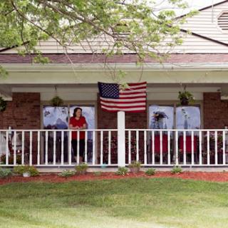 A welcoming porch adorned with an American flag, featuring people enjoying their time outdoors.