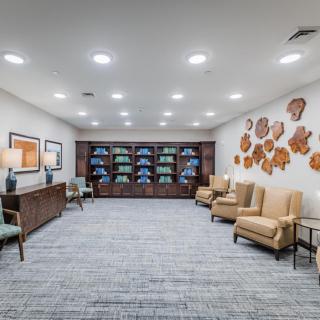 A modern waiting room featuring comfortable seating, decorative wall art, and neatly arranged shelves.
