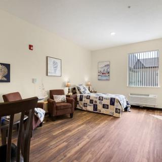 A cozy room with a single bed and comfortable chairs, featuring warm lighting and tasteful decor.