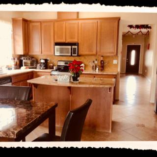 A modern kitchen with wooden cabinets, a central island, and dining area.