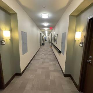 A long, well-lit hallway featuring multiple doors and a clean, modern interior.