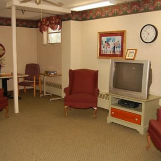 A vintage-themed living room with armchairs, a CRT television, and wall decor.