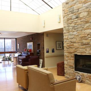 A modern living room featuring a stone wall with a built-in fireplace and natural lighting from skylights.