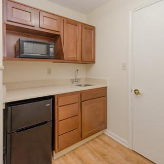 A compact kitchen area featuring wooden cabinets, a microwave, and a small sink.