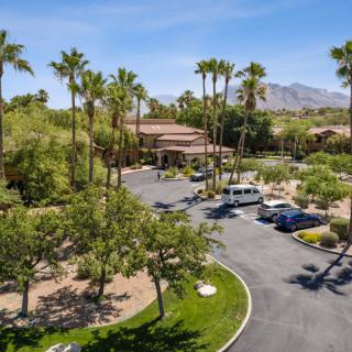 A desert resort with palm trees, a parking lot, and distant mountains under a clear blue sky.