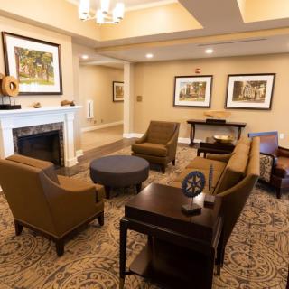 A cozy living room with comfortable seating and a fireplace, adorned with artwork on the walls.