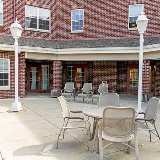 A patio area with chairs and a table outside a brick building.