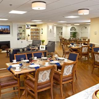 A well-lit, cozy dining area with wooden tables and chairs arranged neatly for communal use.