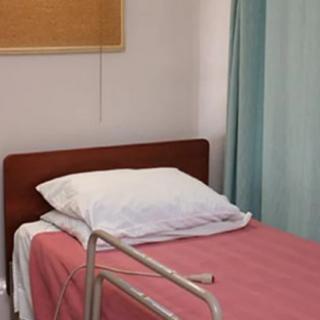 A hospital room featuring a single bed with pink bedding and a privacy curtain.