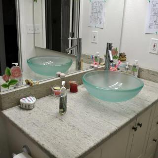 A modern bathroom with a glass bowl sink and vanity mirror.