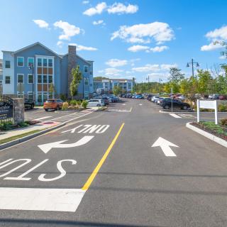 A residential area with a parking lot and road markings on a sunny day.