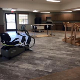 A spacious rehabilitation center featuring exercise equipment and bright interior design.