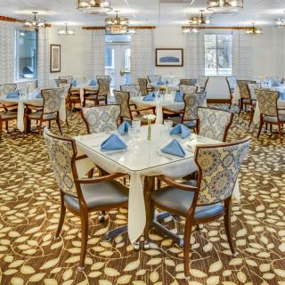 Elegant dining room with neatly set tables and patterned carpet.