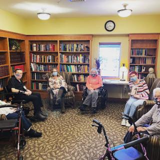 A group of seniors gathered in a library for an engaging reading session.