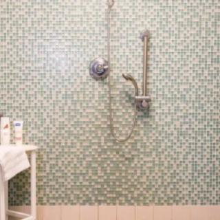 A modern bathroom with green tiled walls and a shower setup.