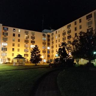 An illuminated apartment complex surrounded by trees at night.