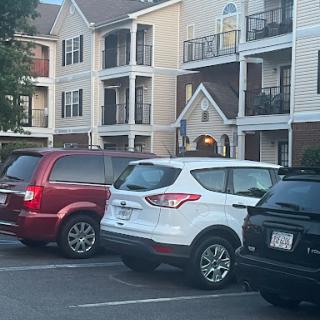 A view of parked cars in front of an apartment building.