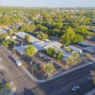 An aerial view of an urban neighborhood with a visible intersection and residential buildings surrounded by greenery.