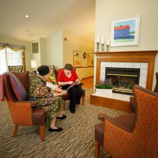 Two people sitting in a cozy living room, engaging in conversation near the fireplace.