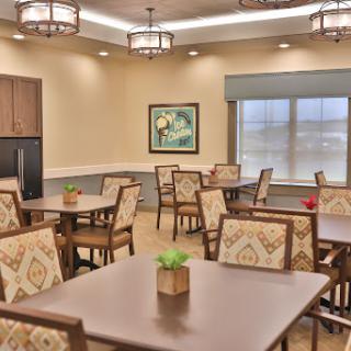 A well-lit dining area with neatly arranged tables and chairs, featuring decorative plants.