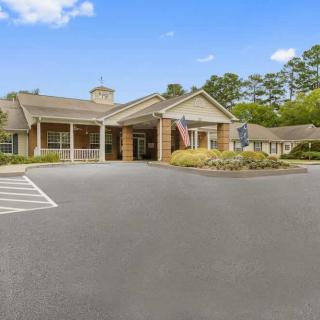 A single-story building with a landscaped entrance and parking area on a clear day.