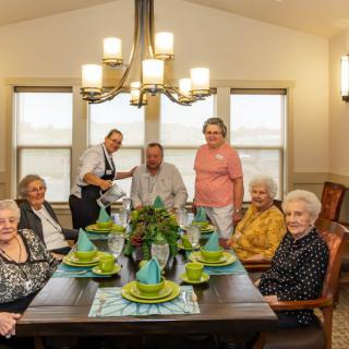 A group of people gathered around a dining table set for a celebration.