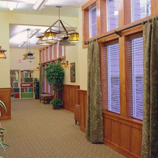 A cozy hallway with wood paneling, large windows, and decorative lighting.