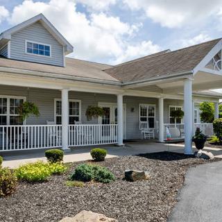A charming residential home with a front porch and landscaped yard on a sunny day.