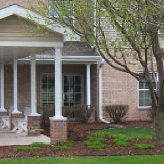 A charming residential house featuring a welcoming porch and well-maintained landscaping.