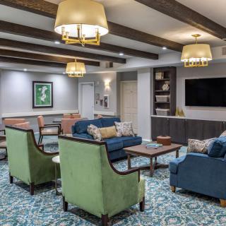 A cozy living room with colorful seating, decorative beams, and a large television.