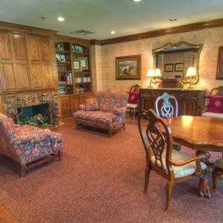A traditional living room with a cozy fireplace, surrounded by bookshelves and classic furniture.