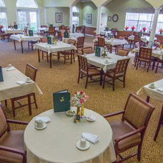A spacious dining room with neatly arranged tables and chairs, featuring place settings and menus on each table.