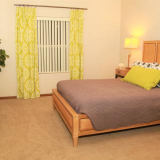 A modern and minimalist bedroom featuring a wooden bed, soft lighting, and vibrant green curtains.