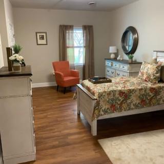 A cozy bedroom with floral bedding, an orange armchair, and stylish decor.