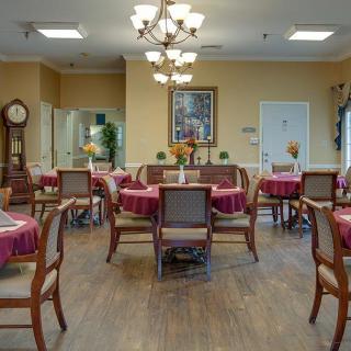 A cozy dining room with neatly arranged tables and chairs, featuring warm lighting and elegant decor.