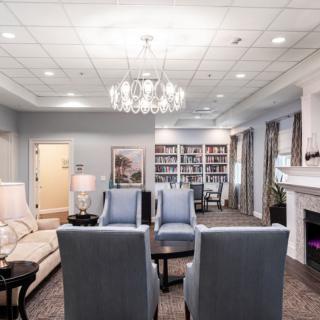 A cozy living room with modern decor, featuring a chandelier, comfortable seating, and a well-stocked bookshelf.