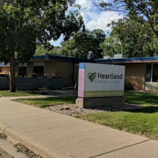 Exterior view of the Heritage facility with a sign in front surrounded by greenery.