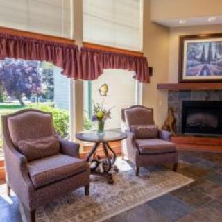 A cozy living room with two armchairs facing a fireplace, accompanied by a small round table and decorative elements.