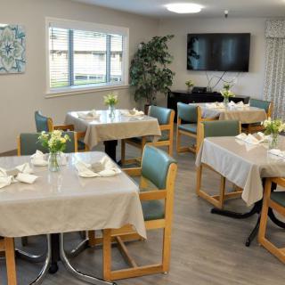 A cozy dining area with neatly set tables adorned with flowers.