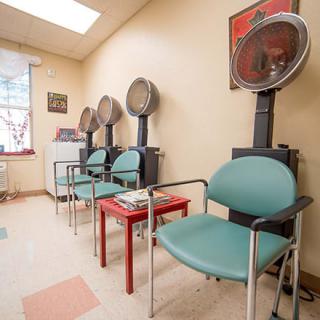A cozy hair salon waiting area with dryers and comfortable seating.