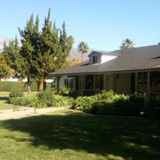 A suburban house with a well-maintained lawn and lush greenery.