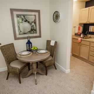 A cozy dining area with a small table and two chairs adjacent to a kitchen, featuring modern decor.