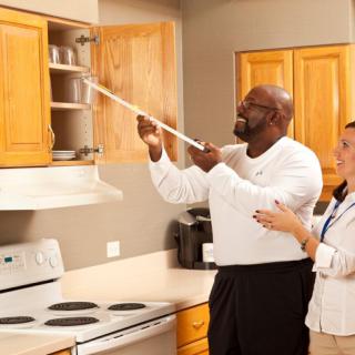 Two people measuring a kitchen cabinet with a measuring tape.