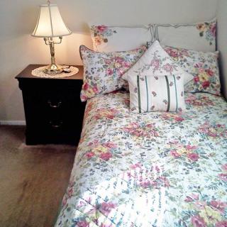 A cozy bedroom with floral bedding and a lamp on the nightstand.