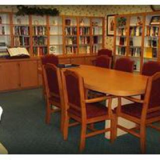 A cozy library reading area with a wooden table and chairs surrounded by bookshelves.