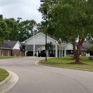 A residential or commercial building surrounded by trees with a road leading to it.