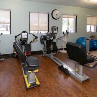 A fitness room equipped with various exercise machines including a rowing machine and stationary bike.
