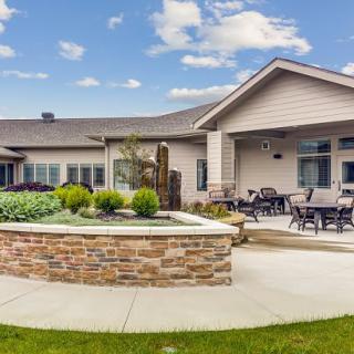 A modern house with a spacious patio and landscaped garden under a blue sky.